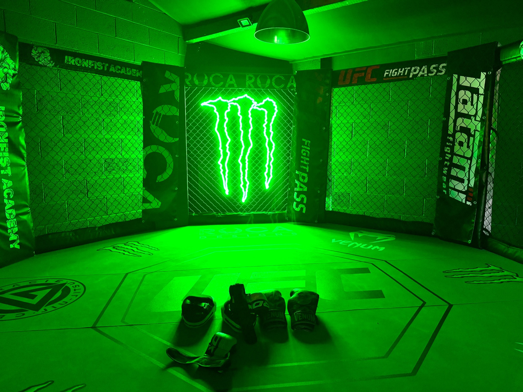 Iron Fist Academy MMA cage lit in Monster Energy green neon